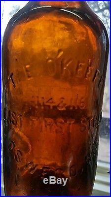 Antique O'Keefe stoneware jug & embossed glass bottle Oswego New York whiskey